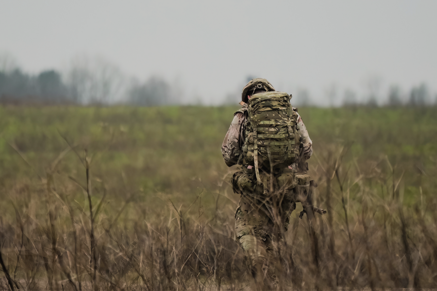 British soldier walking through field on exercise